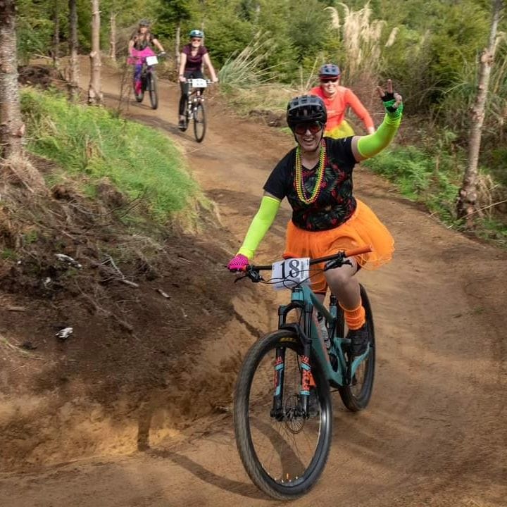 Jenna Rowe mountain biking in a orange skirt.