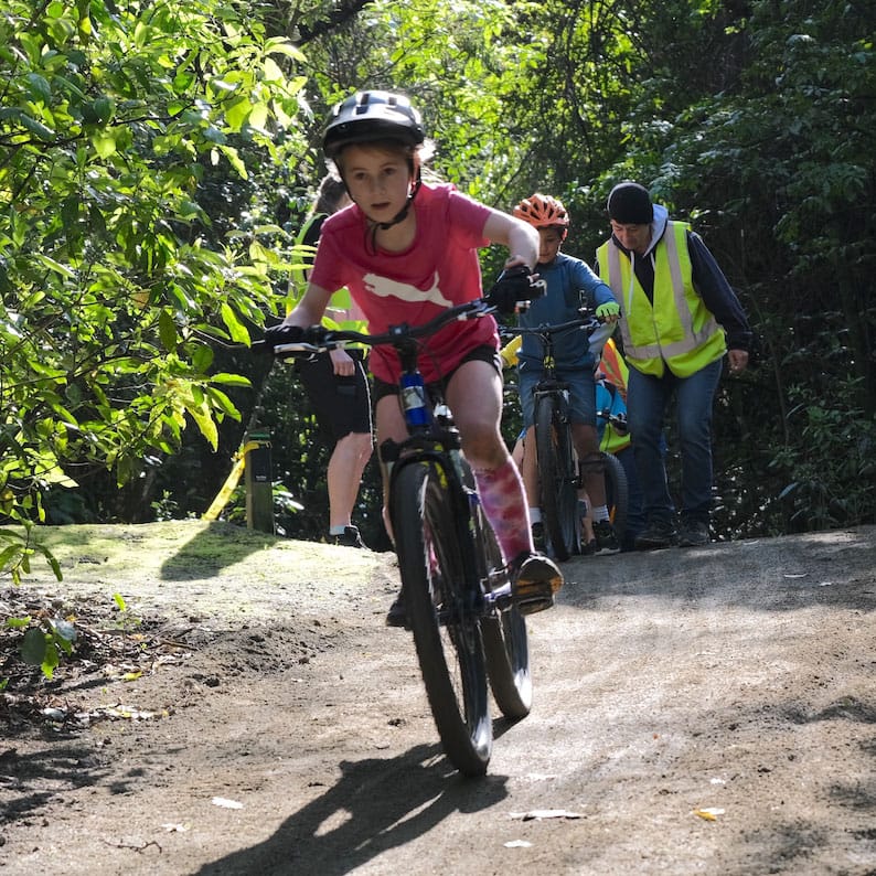 A young girl riding down a sloping trail.